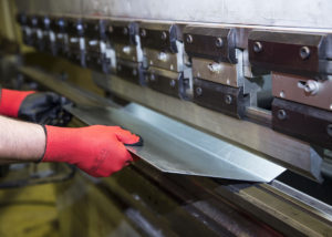 A man inserting the sheet in CNC metal press machine